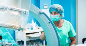 Medical assistant in the operating room verifying orthopedic surgeons work on a human spine, with the help of a c- arm fluoroscope.