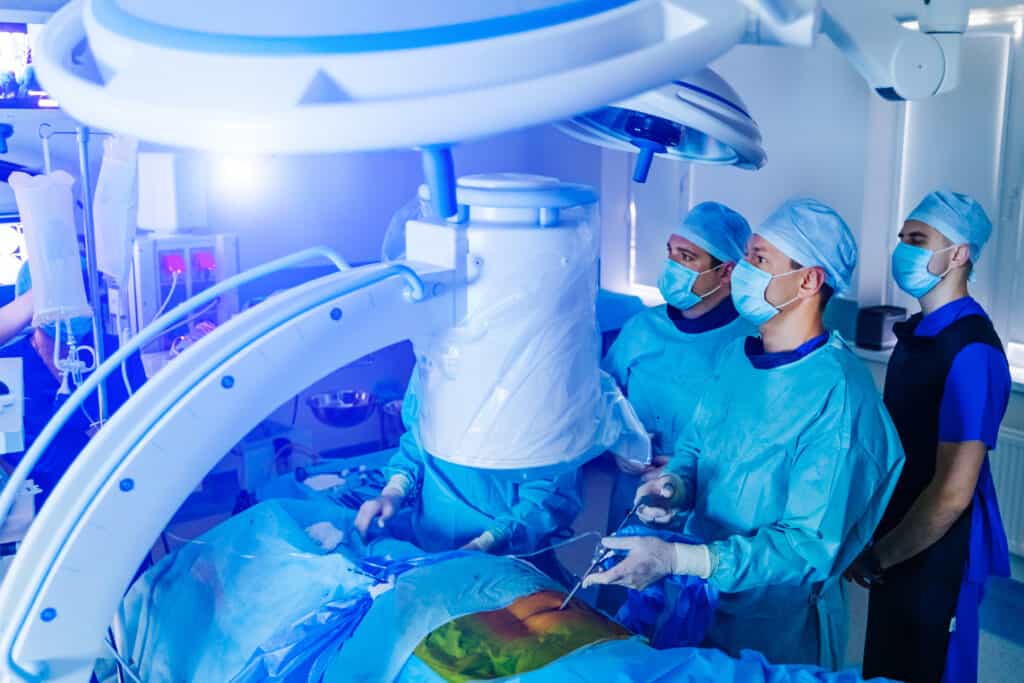 Spinal surgery. Group of surgeons in operating room with C-Arm machine. Laminectomy. Flat panel detectors vs. image intensifiers
