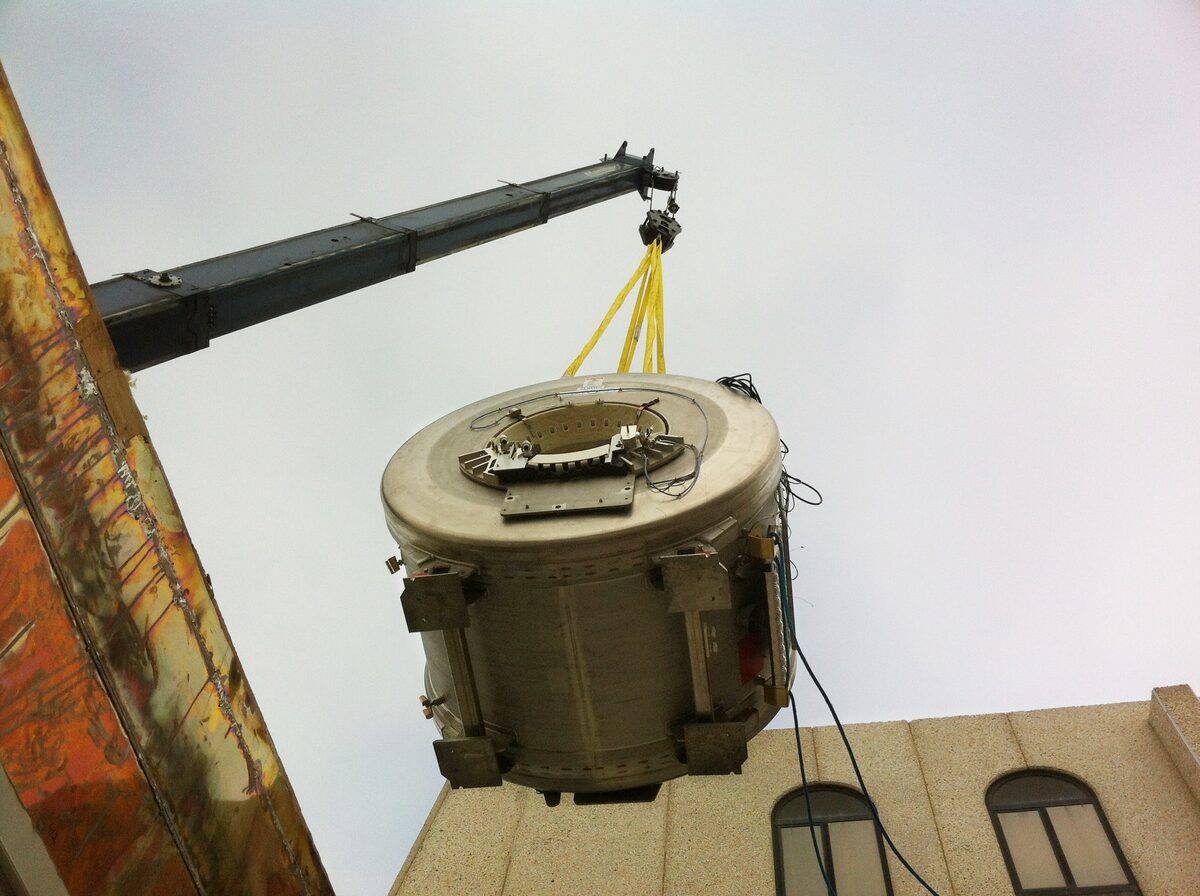Crane removing a used MRI magnet from a medical facility during deinstallation